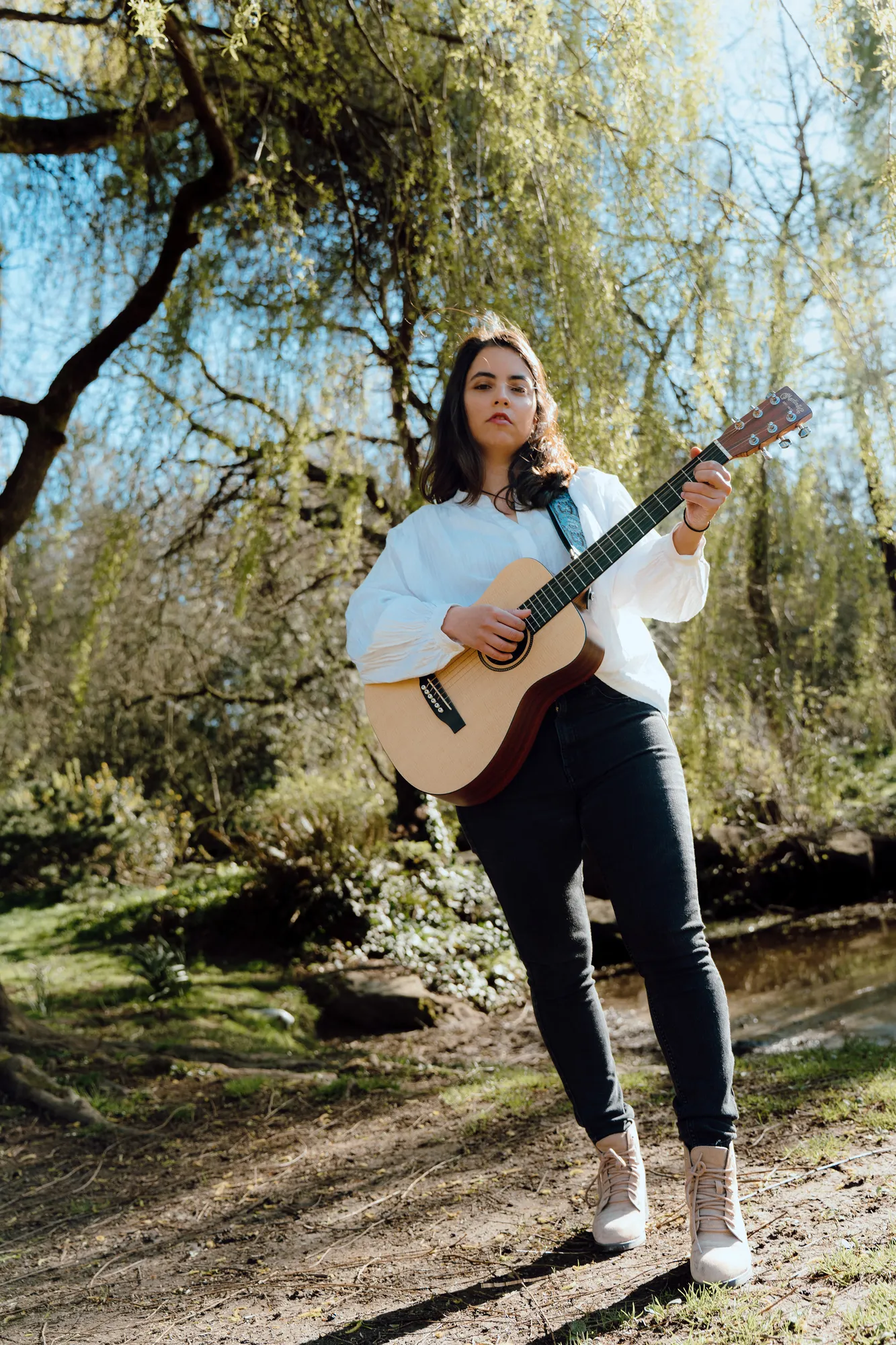 Ani playing guitar under the willow branches on a sunny day