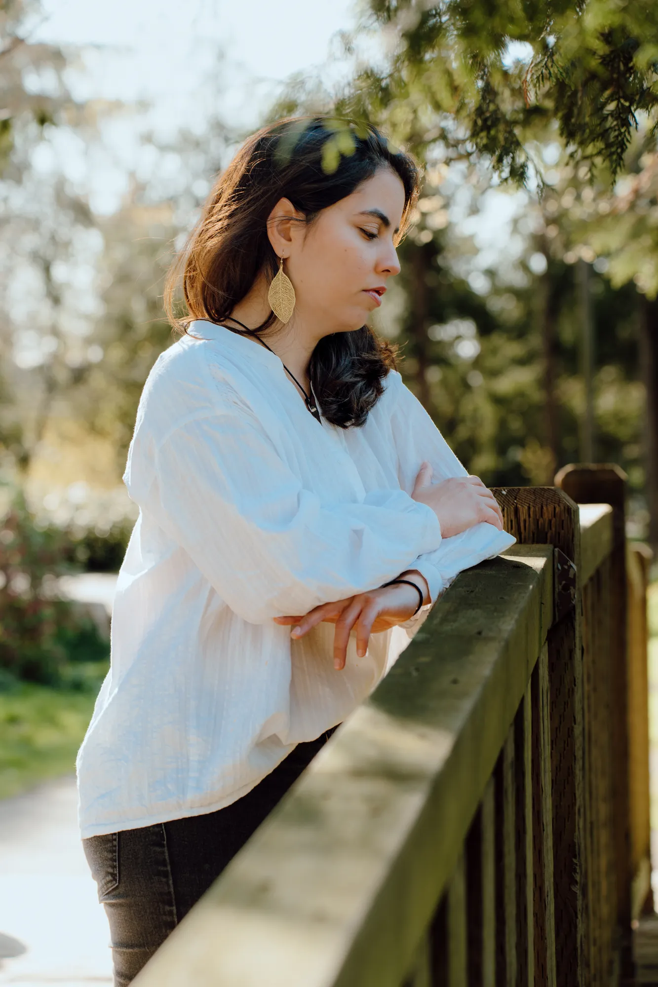 Ani resting her arms on a wooden bridge railing, eyes closed