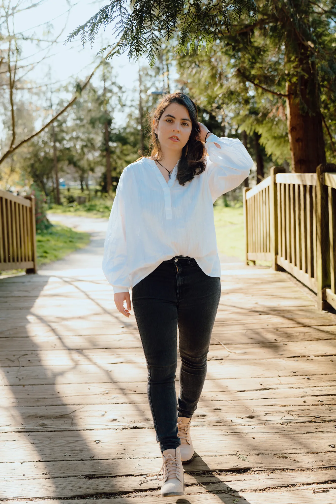 Ani walking across a wooden footbridge in the park
