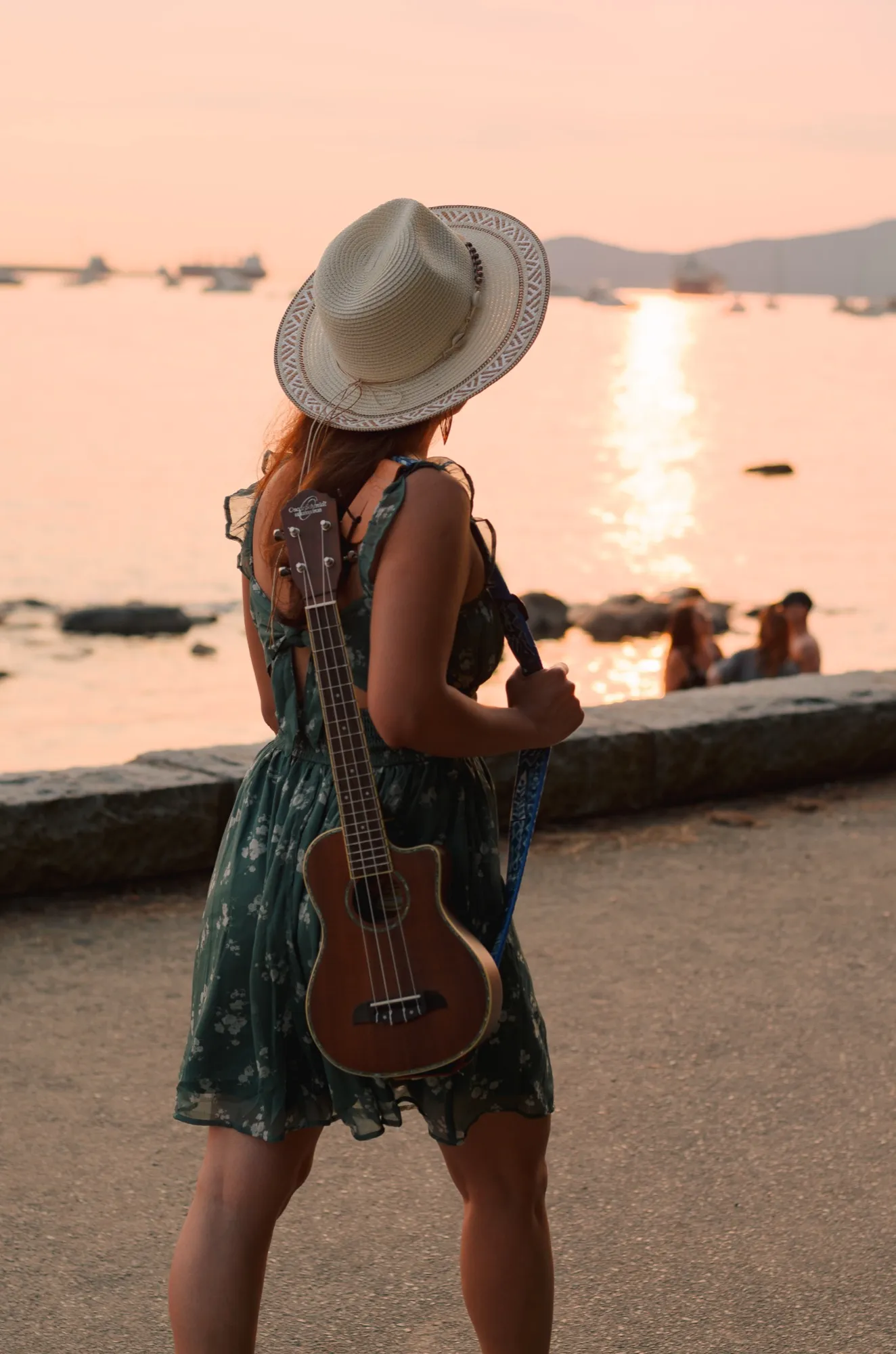 Ani walking along the seawall with her ukulele on her back