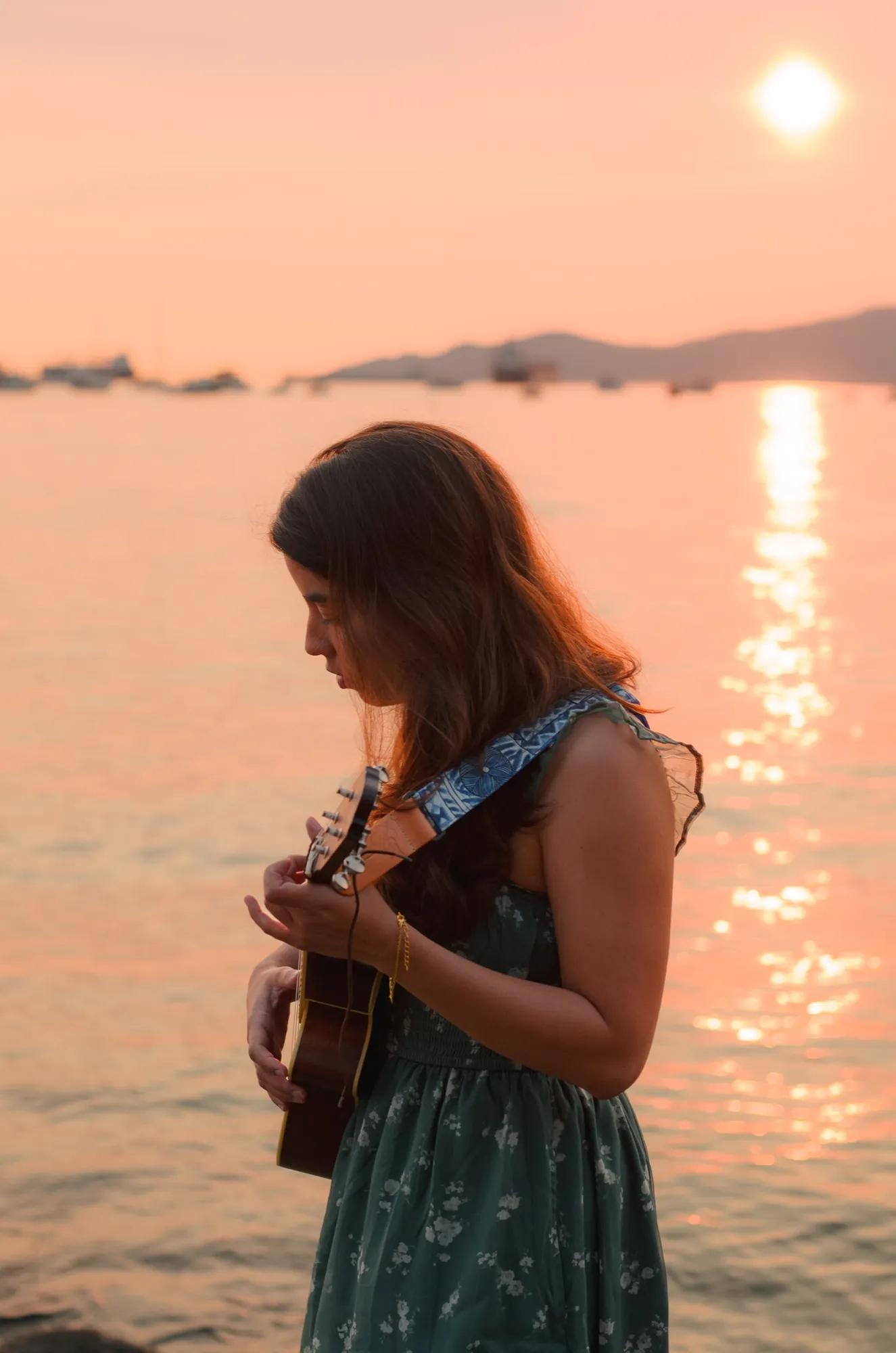 Ani playing ukulele by the water at sunset